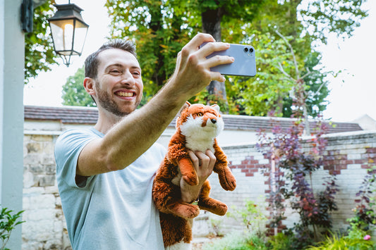 Man taking a selfie with a tiger plush toy.