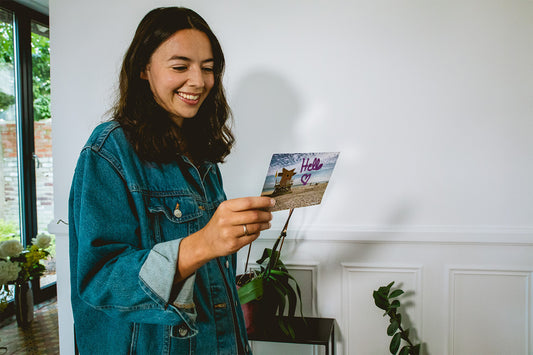 Smiling woman reading the back of a postcard from Lovebox.